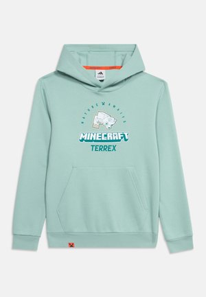 Sweat à capuche vert clair avec poche frontale, logos Minecraft et Terrex, et graphique d’un ours polaire en blocs au-dessus du texte "Nature Awaits"