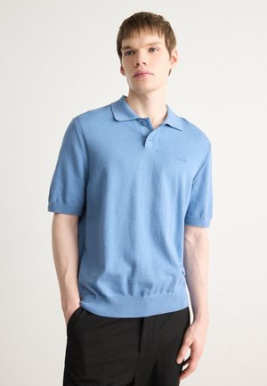 Lichtblauw poloshirt met korte mouwen, voorzien van een geribde kraag en zoom, met een subtiele logo op de linkerborst. Zachte stof, casual pasvorm.
