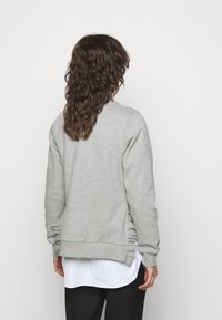 Hellgrauer Sweatshirt mit lässigem Schnitt, gerippten Bündchen und Rüschendetails an den Seiten. Aus weichem Material gefertigt und mit klassischem Rundhalsausschnitt.
