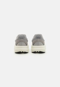 Szürke hálós és velúr slip-on cipők fehér, vastag középtalp és fekete gumitalp jellemzi, texturált hátsó panellel és minimális márkázással.