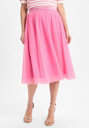 Pink tulle skirt with a wide waistband, knee-length design, and layered fabric texture. Gold strappy sandals complement the outfit.