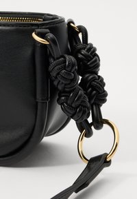 Black leather handbag with a round shape. Features a braided strap, gold hardware, and a smooth texture with visible stitching.