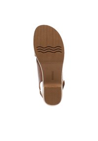 Brown sandal with a textured rubber sole featuring wave patterns and a smooth top. The shoe has a minimalist design with adjustable straps.