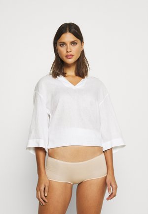 Witte linnen cropped top met een V-hals en brede mouwen, gecombineerd met beige naadloze onderkleding. De stof heeft een subtiele textuur.