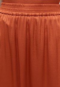 Jupe couleur rouille avec taille élastique et détails en tissu doux et froncé.