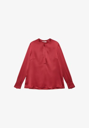 Rote Satinbluse mit langen Ärmeln, Rundhalsausschnitt, dezentem Falten-Detail an der Vorderseite und leicht ausgestellten Manschetten an den Ärmeln.