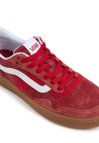 Røde sneakers i semsket skinn med en hvit side stripe, klassisk snøring, perforerte detaljer på tåen, og en brun gummisåle.
