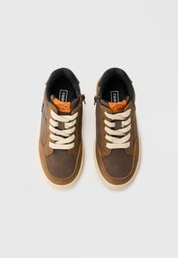 Sneakers din piele maronie și textil, cu șireturi de culoare crem, guler negru, accente portocalii și o talpă de cauciuc bej. Dispune de un fermoar lateral pentru o purtare ușoară.