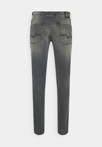 Jeans de mezclilla oscuros ajustados de corte slim con un acabado desgastado, que cuentan con dos bolsillos traseros con costuras curvas y una cinturilla estándar.