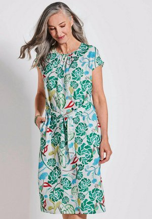 Blumenkleid aus leichtem Stoff mit grünen Blättern, roten Akzenten und blauen Blumen. Kurze Ärmel, lockere Passform mit einem gebundenen Taillendetail.