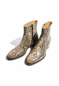 Stivali alla caviglia in pelle di serpente con punta appuntita, dotati di una cerniera laterale e rivestimento in pelle liscia a contrasto. Toni prevalentemente beige e marroni.