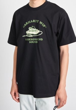 T-shirt en coton noir avec un motif graphique vert affichant le texte « Carhartt WIP® Underground Sound » et une illustration de platine vinyle.