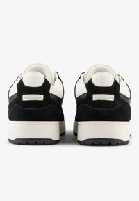 Black suede sneakers with white mesh accents, a padded collar, and a cream rubber sole. Features logo detail on the heel.
