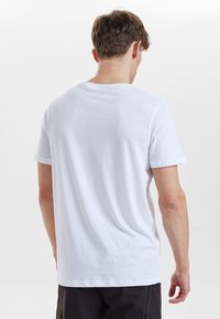 Hvid bomulds T-shirt med rund halsudskæring og korte ærmer, med en glat tekstur og en afslappet pasform. Bagudsigten.
