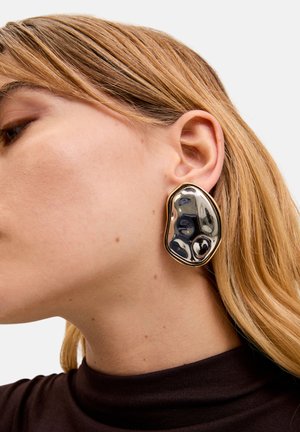 Orecchini grandi di forma astratta presentano un design lucido nero e metallico con una texture superficiale irregolare, rifiniti in metallo tono oro.