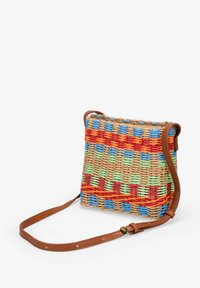 Bolso tejido multicolor hecho de fibras naturales, con una combinación de patrones en azul, verde, naranja y rojo, y una correa de cuero marrón.