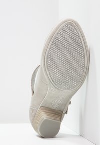 Szare zamszowe buty z teksturowaną podeszwą i subtelnym obcasem, charakteryzujące się plecionym paskiem akcentującym oraz wzorzystą cholewką dla lepszej przyczepności.
