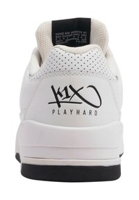 Sneaker bianca con design perforato, suola nera e logo del marchio sul tallone. Presenta un colletto imbottito e materiali texturizzati.