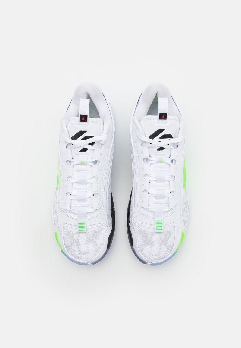 Scarpe da ginnastica bianche con tomaia testurizzata, dettagli verdi, suola nera e un sistema di lacci prominente. Presentano un logo sulla linguetta.