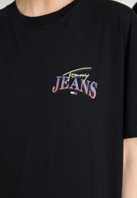 Tricou din bumbac negru cu mâneci scurte. Prezintă un print multicolor al logo-ului "Tommy JEANS" în zona stângă a pieptului. Textură netedă.