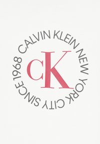 Λευκό ύφασμα με στρογγυλό λογότυπο που γράφει «CALVIN KLEIN NEW YORK CITY SINCE 1968» σε μαύρο, περιβάλλοντας το εμφανές κόκκινο «ck.»