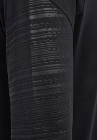 Top sportivo nero a maniche lunghe con un motivo testurizzato sulla spalla e sul braccio. Tessuto liscio con una vestibilità aderente.