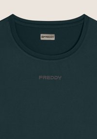 Camiseta de manga corta verde oscuro con cuello redondo. Presenta un sutil logo "FREDDY" en un tono más claro en la parte delantera. Textura suave.