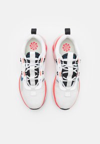 Bílé sportovní boty s síťovinovým svrškem, černými šňůrkami, korálovými akcenty a modrým logem. Mají polstrovanou podrážku a výrazný květinový vzor uvnitř.