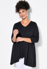 Schwarze Bluse mit V-Ausschnitt, 3/4-Ärmeln und plissiertem Design. Der weiche Stoff fällt über einen weißen Hintergrund und sorgt für eine lockere Passform.