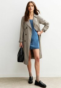 Trench coat a cuadros beige, vestido azul de mezclilla, loafers negros, calcetines beige. Diseño moderno con botones, cuello y texturas variadas.