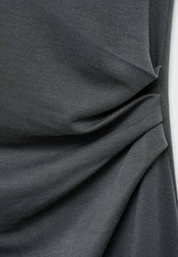 Dark gray fabric with a textured weave, featuring soft folds and creases that create depth and visual interest.
