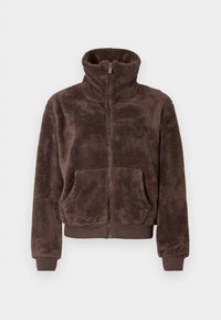 Bruine fleece jas met hoge kraag, volledige rits en voorzakken. Heeft ribgebreide mouwen en zoom, een zachte textuur en een ontspannen fit.