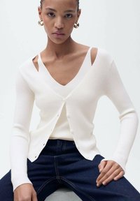 Rippstrick-weiße Strickjacke mit tiefem V-Ausschnitt und Cut-Out-Details an den Schultern, mit Knöpfen an der Vorderseite und langen Ärmeln.