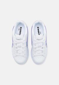 Hvite sneakers med lilla detaljer, skinnøvre, rund tå, teksturert såle og snøring. Har logo på tungen og siden.