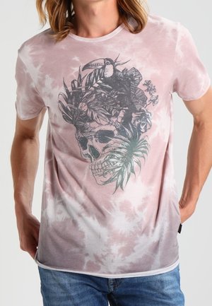 T-shirt tie-dye rose clair avec un motif détaillé de crâne noir orné de plantes tropicales et d'un toucan, manches courtes, col rond.