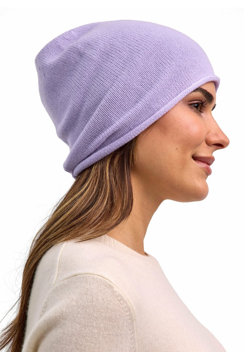 Beanie di colore viola chiaro realizzata in morbido materiale a maglia, con un design slouchy e superficie liscia, indossata leggermente inclinata sulla testa di un modello.