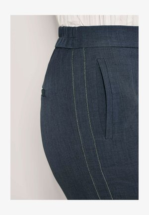 Donkerblauwe broek met een gestructureerde afwerking, voorzien van een brede elastische tailleband, zijzakken en contrasterende lichte stiksels langs de naden.