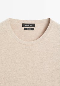 T-shirt girocollo in cotone beige con una texture liscia. Presenta l'etichetta del marchio "Massimo Dutti" sul colletto e un'etichetta con le informazioni per la cura sottostante.