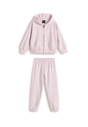 Lys pink lynlåshoodie med kængurulommer og matchende joggingbukser med elastisk talje, begge med et lille hvidt Vans-logo.