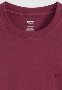 Bordeauxfarbens T-Shirt mit Rundhalsausschnitt aus Baumwolle; verfügt über ein kleines geprägtes Logo auf der Brust und einen gerippten Halsausschnitt, mit einem Vintage-Fit-Design.