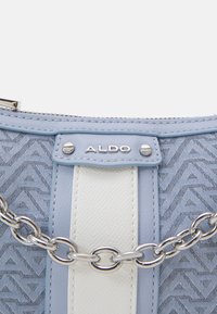 Sac à main en cuir bleu clair et blanc avec tissu à motif triangulaire, bandoulière chaîne argentée et plaque logo ALDO à l'avant.
