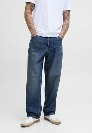Blue denim wide-leg jeans with a slightly faded finish, featuring traditional pockets and a relaxed fit, paired with white sneakers.