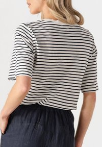 Gestreepte top met korte mouwen in creme en marineblauw, met een casual pasvorm en ronde hals, gecombineerd met donkerblauwe textuurbroek.