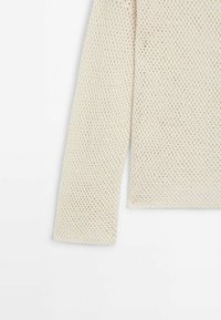 Kremfarvet strikket sweater med løs tekstur. Har en bred halsudskæring og lange ærmer, der viser et diamantmønster over hele.