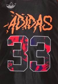 Svart atletisk tröja med "ADIDAS" i orange graffiti-liknande bokstäver och stort röd-blått broderat "33" på baksidan.