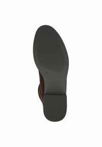Suela de zapato de ante marrón con agarre de goma negra texturizada, con un tacón plano y una puntera redondeada. Diseño limpio sin marcas visibles.