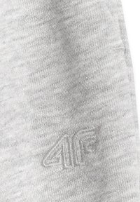 Tissu gris clair avec un logo brodé en relief combinant le chiffre 4 et la lettre F dans une couleur de fil assortie.