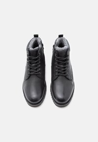 Černé kožené kotníkové boty se šněrováním vpředu, šedou umělou kožešinou uvnitř a bočními zipy. Hladký povrch a zaoblená špička.