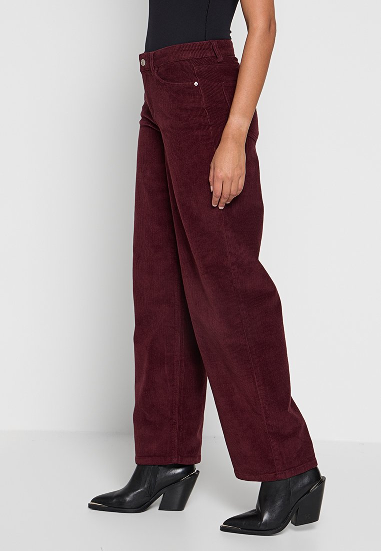 Bordeaux corduroy wijde broek met een hoge taille, gedetailleerde stiksels, voorzakken en een gladde afwerking. Gekenmerkt met zwarte hakken.