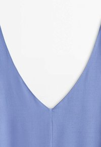 Gros plan sur un tissu bleu clair avec un décolleté en V profond et une couture verticale visible au centre devant.